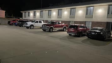 A parking lot with several vehicles parked in front of a building with multiple windows and a brick facade.