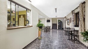 Un pasillo de hotel con suelo de baldosas, muebles de madera y plantas en macetas.