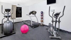 Un gimnasio con cintas de correr, elípticas, una bicicleta estática y pelotas de ejercicio.
