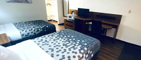 A hotel room with two beds, a desk, a television, and a mirror.