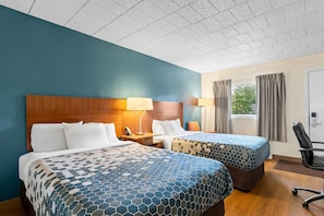 A hotel room with two beds, a wooden headboard, a nightstand with a lamp, a chair, and a window with curtains. - Travelodge by Wyndham Shamokin Dam/Selinsgrove (Shamokin Dam)