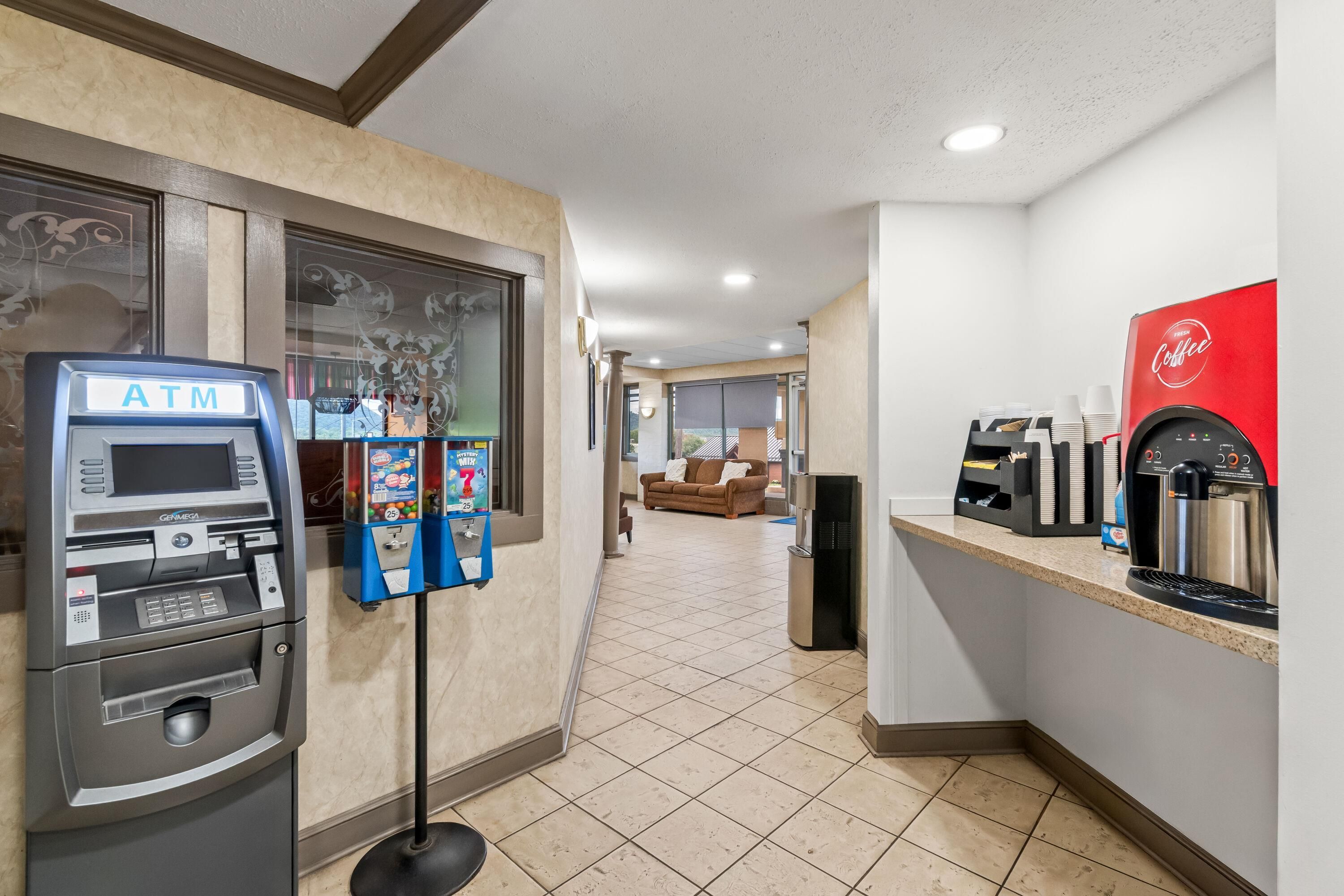 Een binnenruimte met een geldautomaat, een koffiemachine en een zithoek met een bank.