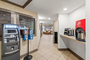 An indoor area with an ATM, a coffee machine, and a seating area with a couch. - Travelodge by Wyndham Shamokin Dam/Selinsgrove (Shamokin Dam)