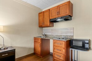 Une cuisine compacte avec des meubles en bois, un plan de travail en granit, un four à micro-ondes encastré et un petit meuble sous le four à micro-ondes.