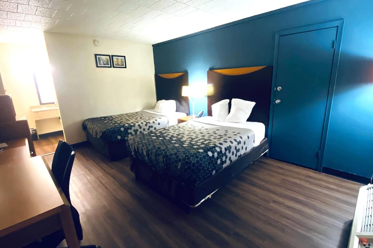 Une chambre d’hôtel avec deux lits, un bureau, une chaise, une armoire et une porte.