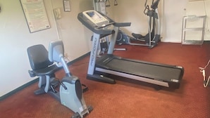 Een fitnessruimte met cardioapparatuur, waaronder een ProForm elliptische trainer, loopband en een hometrainer.
