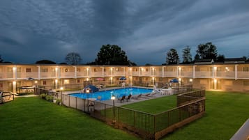 Un hotel amb una piscina envoltada per una zona tancada, diversos balcons i seients a l'aire lliure.