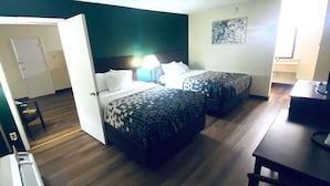 Een hotelkamer met twee bedden, een bureau, een stoel, een deur en een muur met een schilderij.