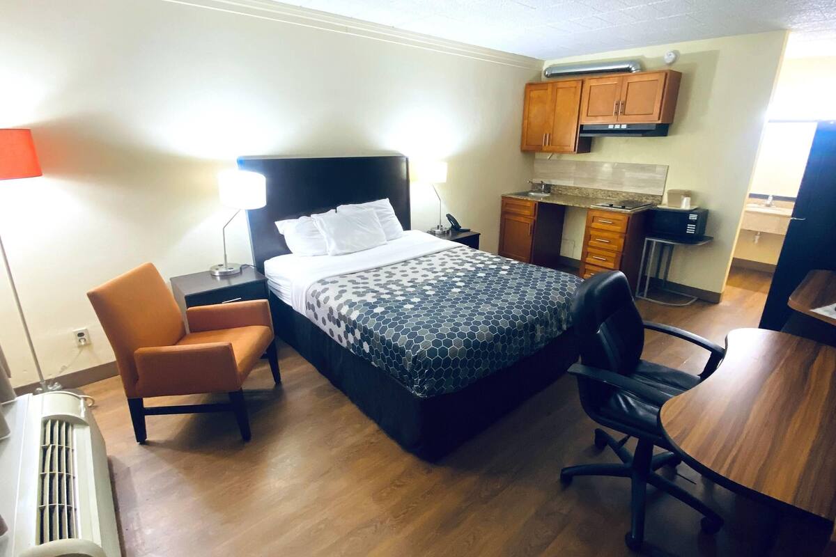 Une chambre d’hôtel équipée d’un lit, d’un bureau, d’une chaise, d’une kitchenette et d’un radiateur.