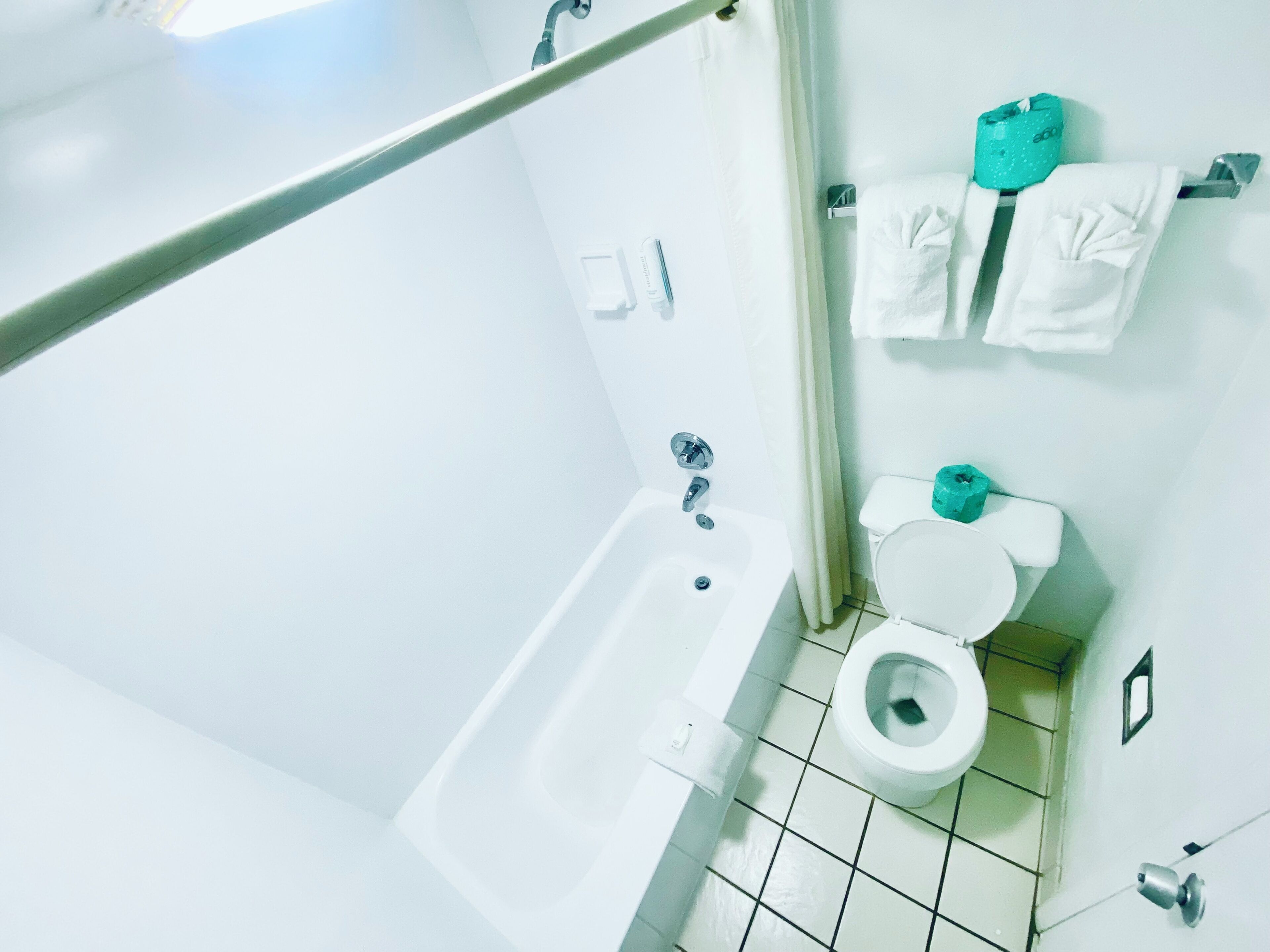 A bathroom with a bathtub, toilet, and a shower curtain rod.