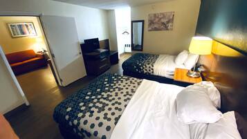 A hotel room with two beds, a desk, a sofa, and a TV.