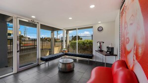 A modern interior with a red sofa, a round table, and a bench along a glass wall. - Rodeway Inn South San Francisco Airport (South San Francisco)