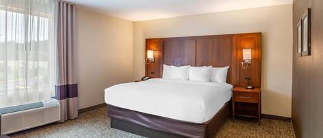Quarto de hotel com cama grande, abajures, aquecedor e janela com cortinas.