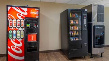 Un espace comprenant des distributeurs automatiques, notamment un distributeur de Coca-Cola, un distributeur de Doritos et un distributeur de glaçons.