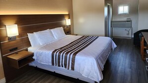 A hotel room with a large bed, bedside tables, a desk, and a kitchenette. - Knights Inn Lindsay (Kawartha Lakes)