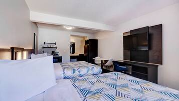 Une chambre d’hôtel avec deux lits, un bureau, un téléviseur à écran plat et une kitchenette.