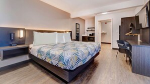 A modern hotel room with a large bed, bedside table, and a small desk area. - Studio 6 Rock Springs WY Flaming Gorge (Rock Springs)