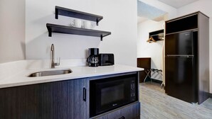 A modern kitchen with a built-in microwave, a coffee maker, and a sink. There is a black refrigerator and a wooden cabinet. - Studio 6 Rock Springs WY Flaming Gorge (Rock Springs)