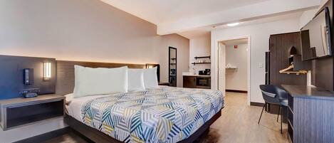Una habitación de hotel moderna con una cama grande, una mesita de noche y un espacio de escritorio con una silla.