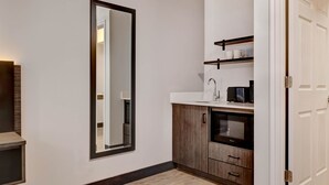A modern bathroom with a large mirror, a sink, and a microwave. - Studio 6 Rock Springs WY Flaming Gorge (Rock Springs)