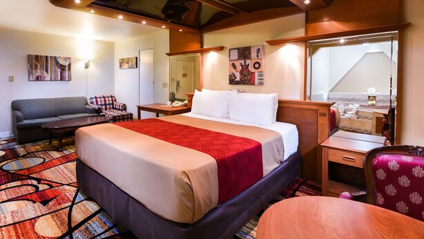 Een hotelkamer met een groot bed, een bank, een bureau en een stoel. Er is een raam met uitzicht op het exterieur.