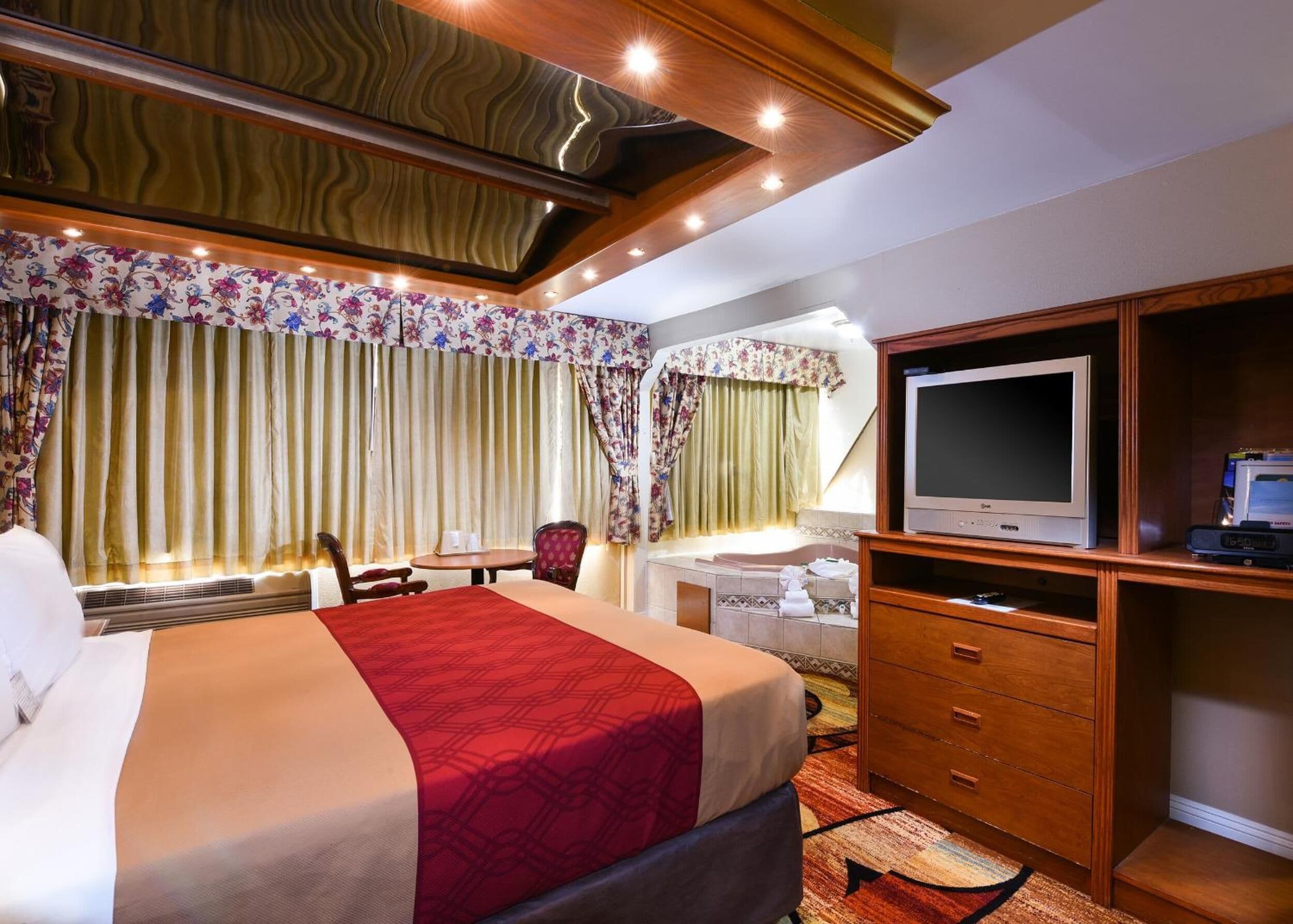 A hotel room with a bed, a TV, a desk, and a bathroom.