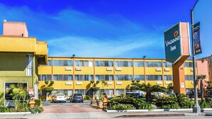 Een geel gebouw met een bord waarop 'Vanguard Inn' staat en een 'Geen parkeren'-bord.