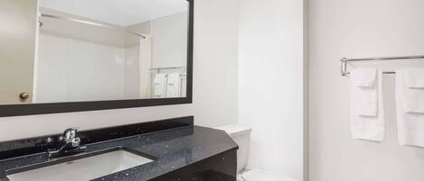A bathroom with a black countertop sink, a white toilet, and a towel rack with white towels.