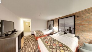 Habitación de hotel con dos camas, televisión, un mural con vista a la ciudad y una pared de ladrillo.