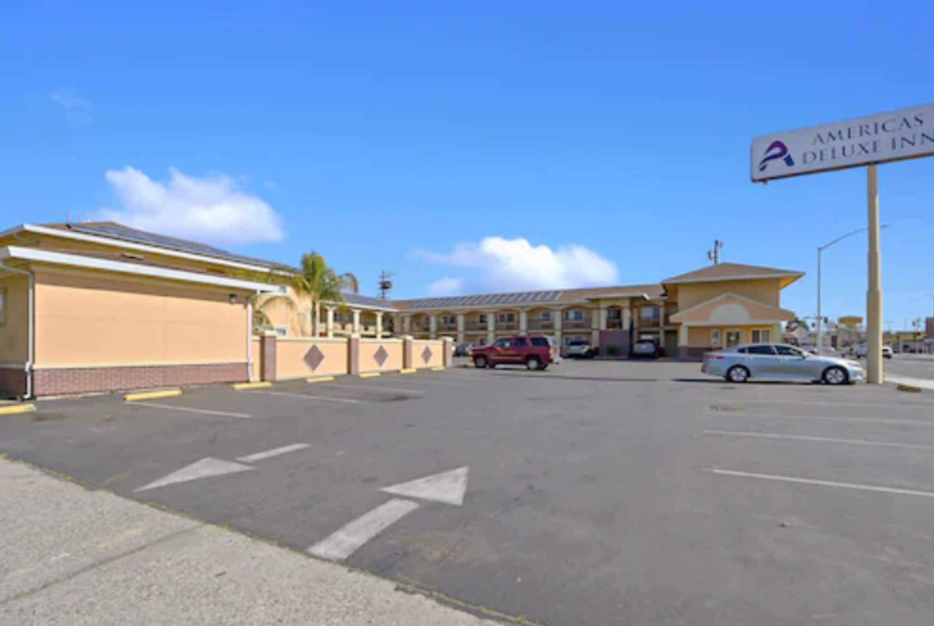A parking lot with a building labeled "AMERICAS DELUXE INN".