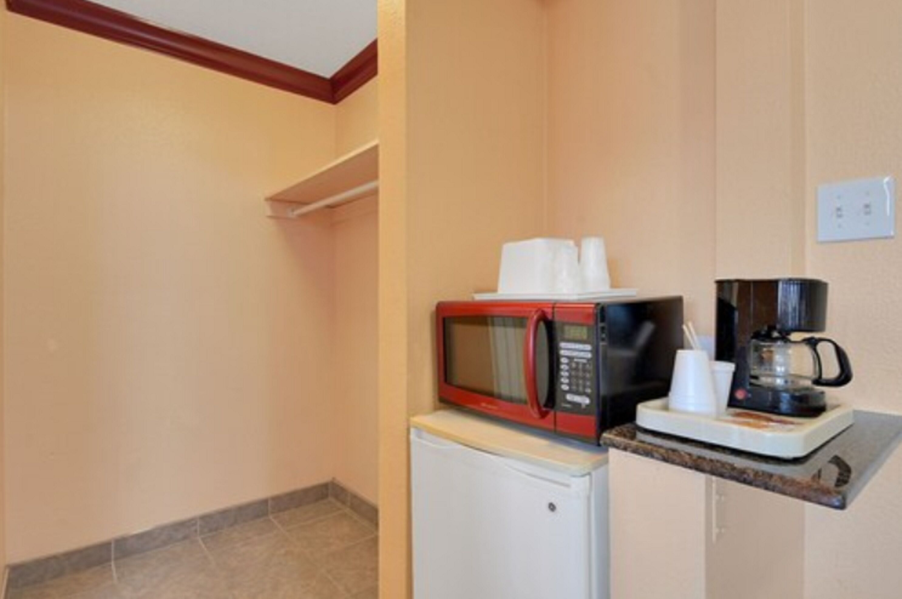 A kitchenette with a microwave, coffee maker, and a small refrigerator.