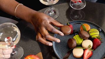 A table with a variety of food items and drinks, including a plate of macarons, strawberries, and a bowl of nuts.