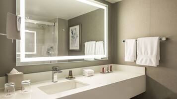 A modern bathroom with a large mirror, white sink, and towel rack.
