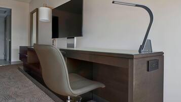 Une chambre d’hôtel moderne équipée d’un bureau, d’une chaise, d’un téléviseur à écran plat et d’une lampe de bureau.
