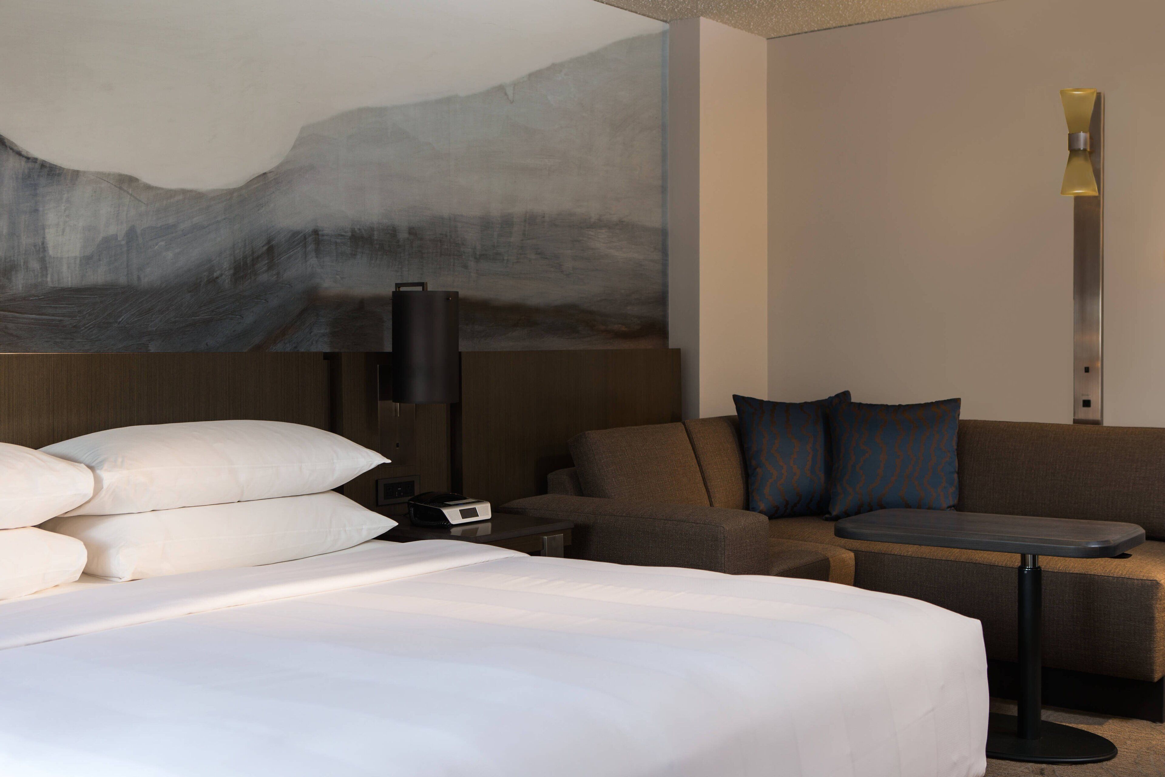 Et moderne hotelværelse med en stor seng, en sofa, et lille bord og en vægmonteret lampe.