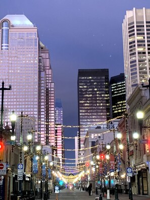 Une rue de la ville bordée d’immeubles imposants et illuminée de guirlandes festives.
