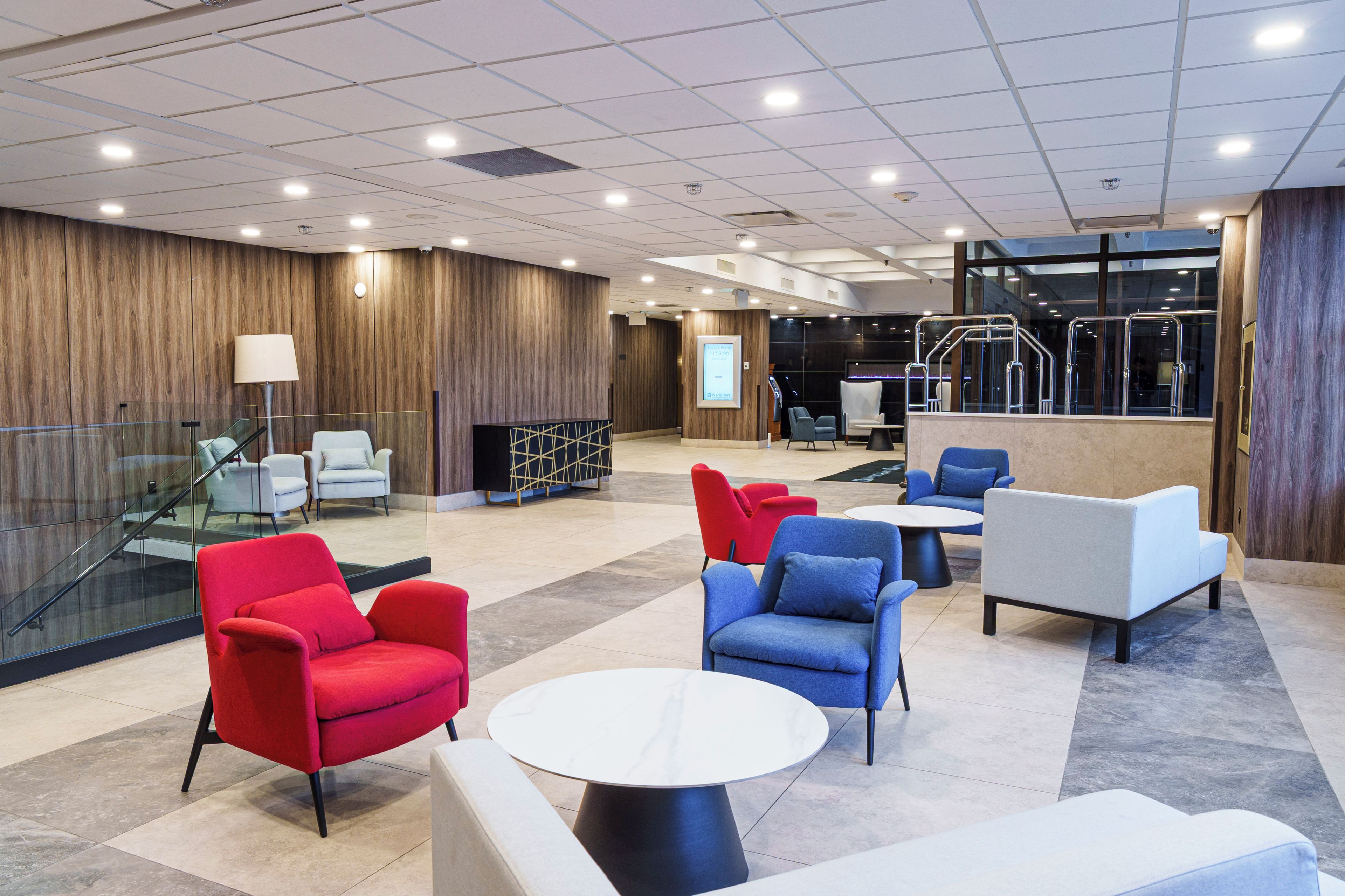 A modern lobby with seating areas, a reception desk, and a staircase.