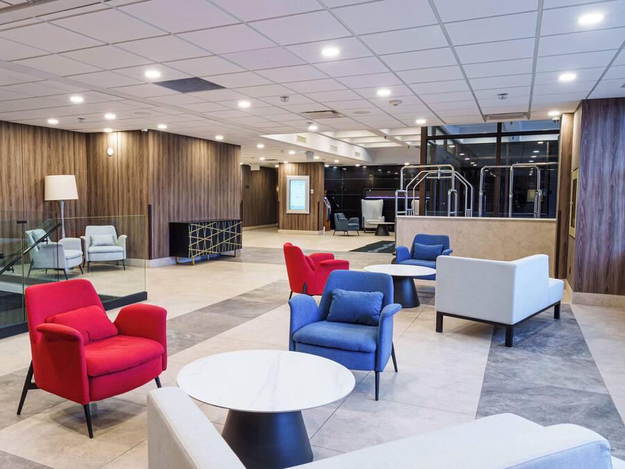 Un vestíbulo moderno con zonas de estar, un mostrador de recepción y una escalera.