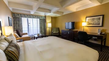 Una habitación de hotel con una cama grande, un escritorio con ordenador, televisor y una silla.
