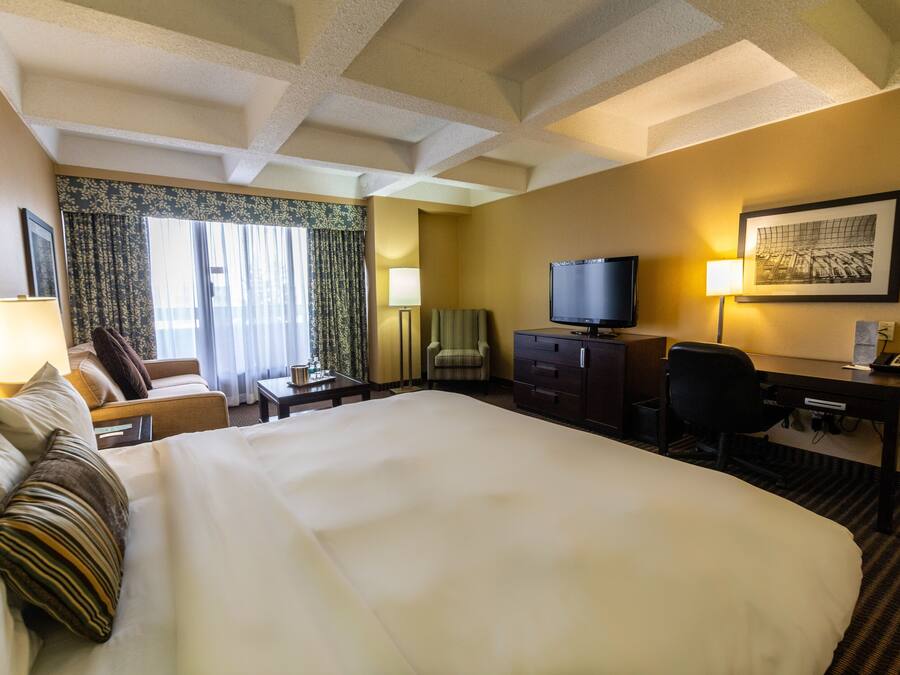 Una habitación de hotel con una cama grande, un escritorio con ordenador, televisor y una silla.
