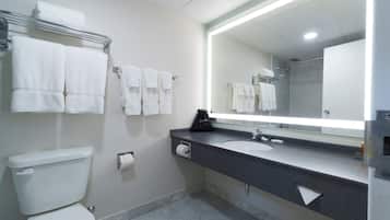 A bathroom with a toilet, a sink, a mirror, and multiple towels on a rack.