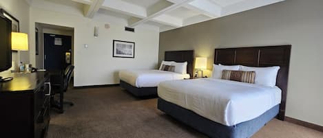 Une chambre d’hôtel avec deux lits, un bureau et une télévision.