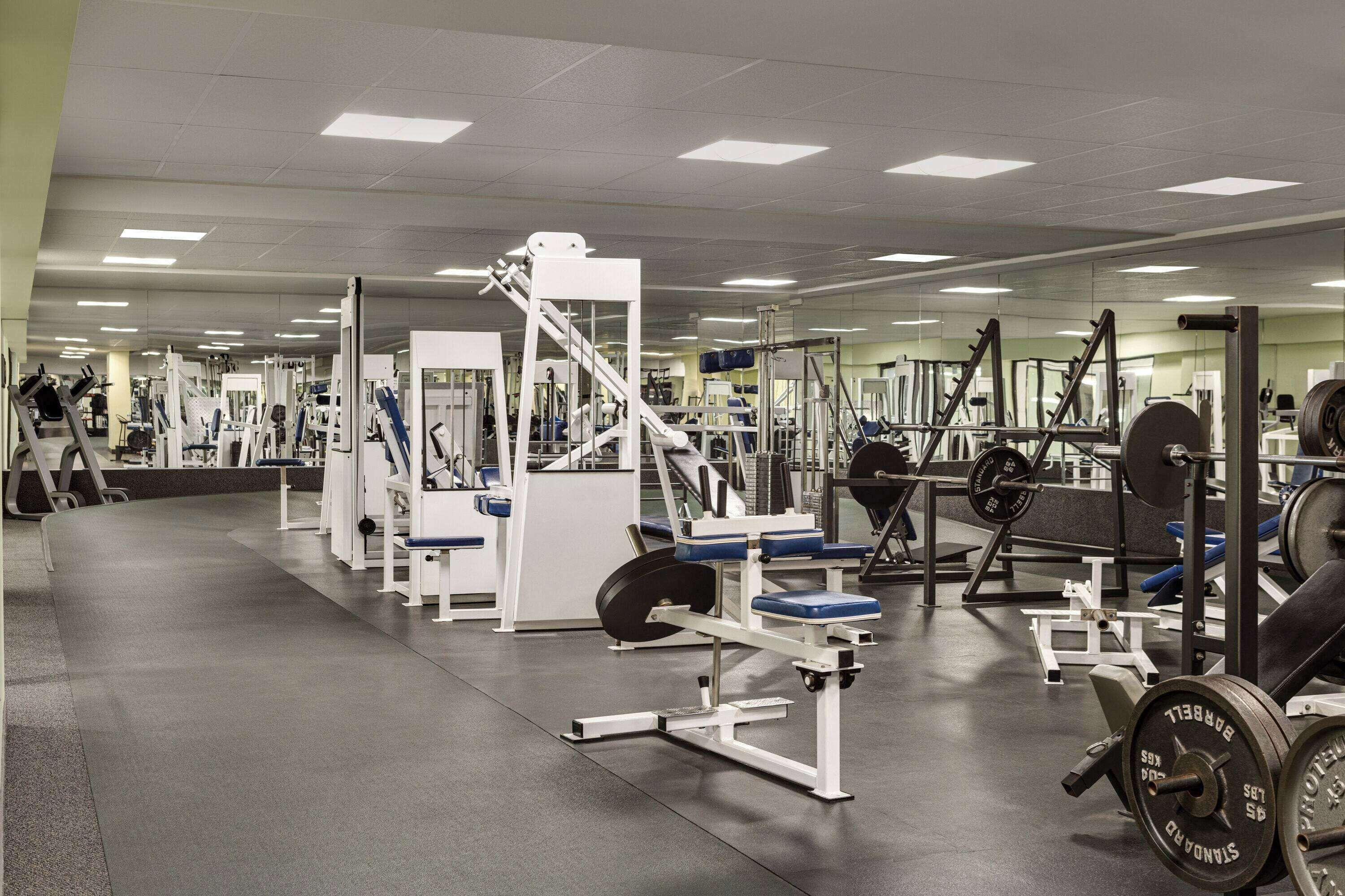 A gym with various exercise equipment, mirrors, and a clean, organized layout.