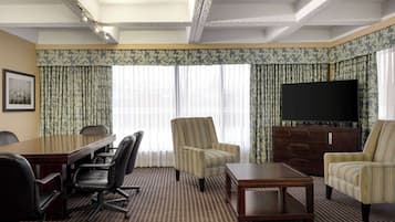 A conference room with a large table, four chairs, a television, and a cabinet.