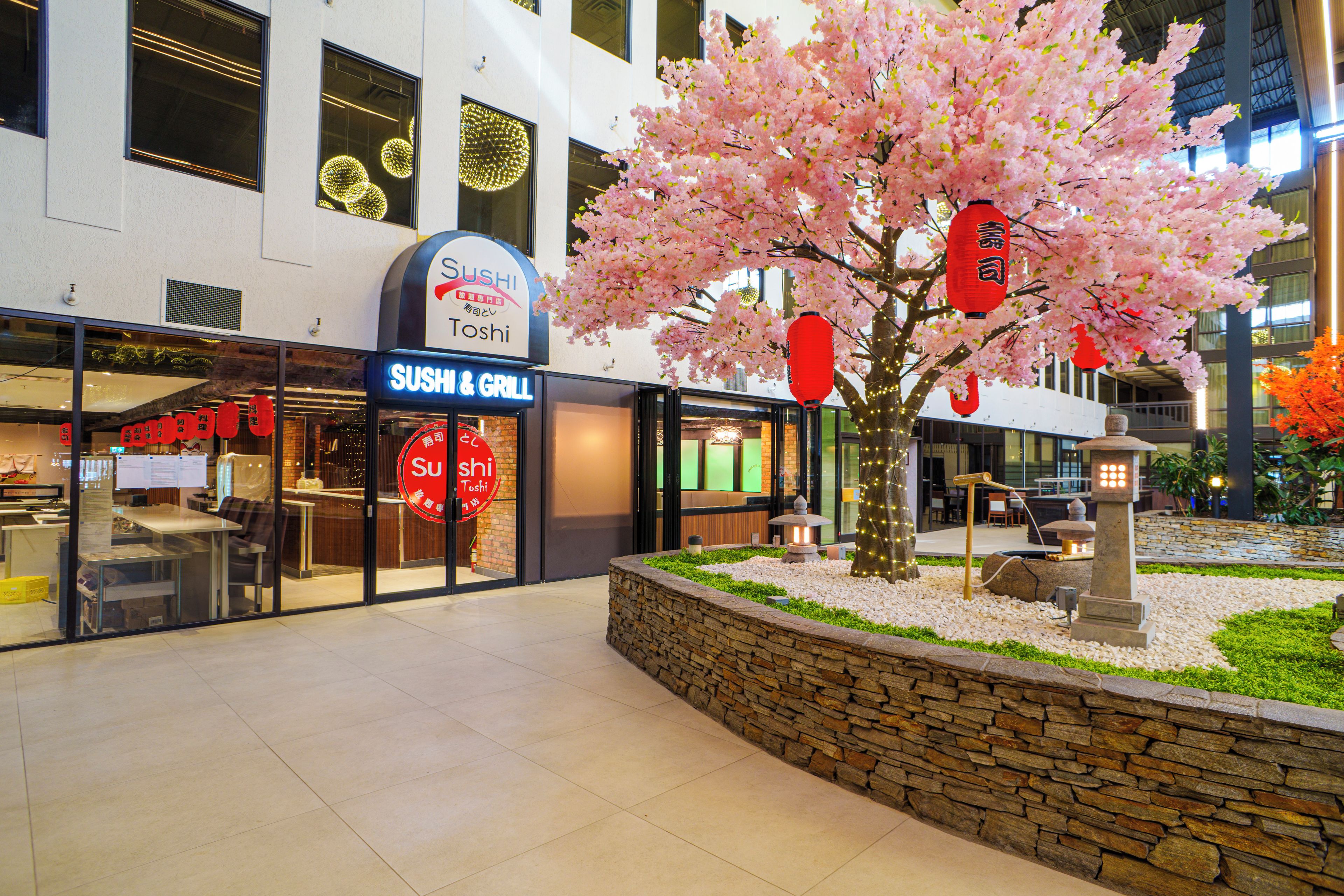 A sushi restaurant with a stone wall and a cherry blossom tree.