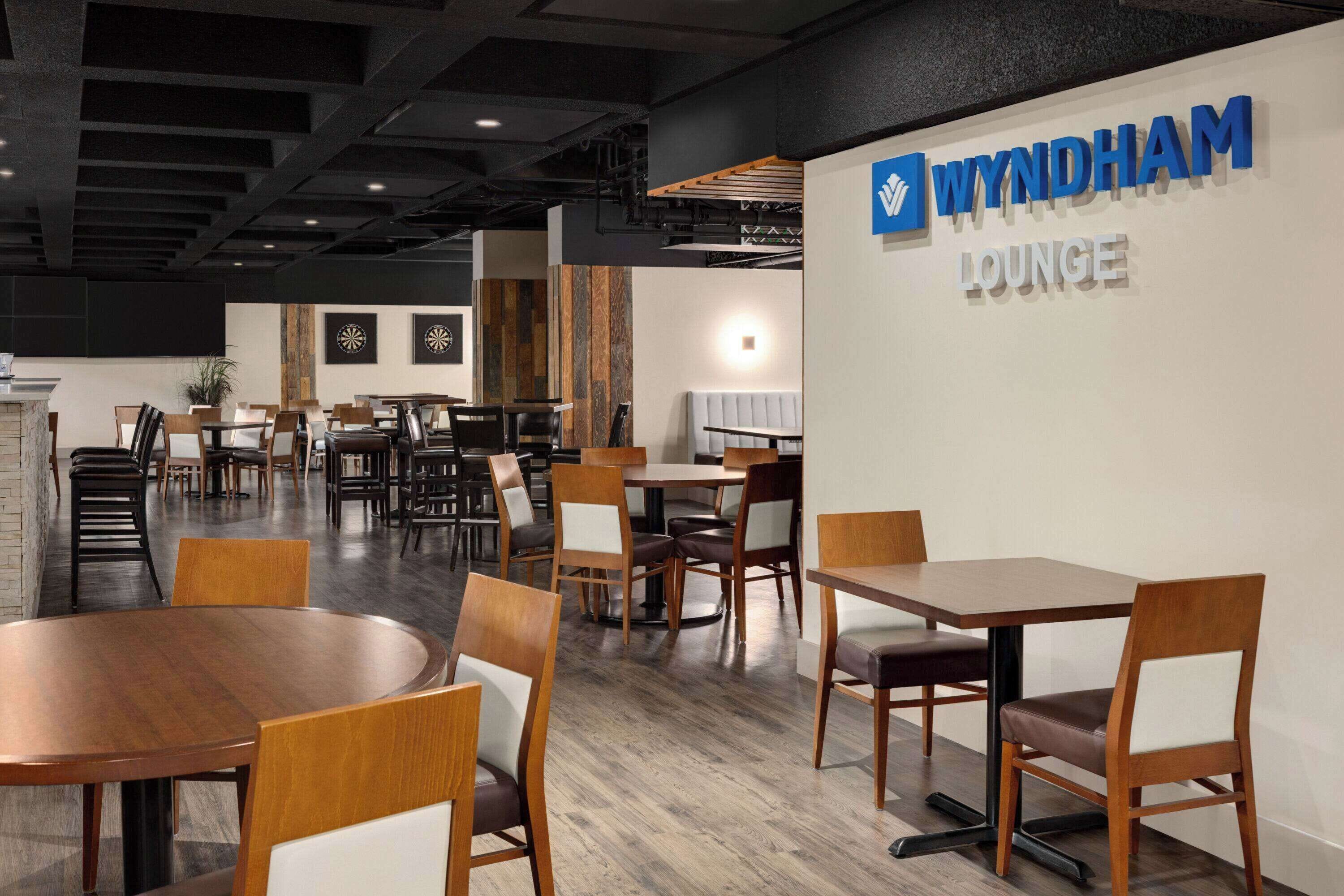 A modern lounge area with multiple seating options, including round and rectangular tables, and a variety of chairs.