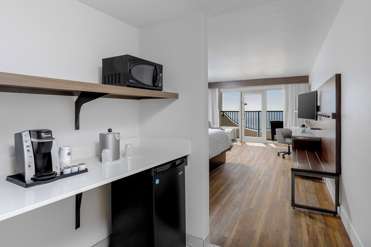 Una habitación de hotel moderna con kitchenette, microondas, cafetera, lavavajillas y vistas a la ciudad.