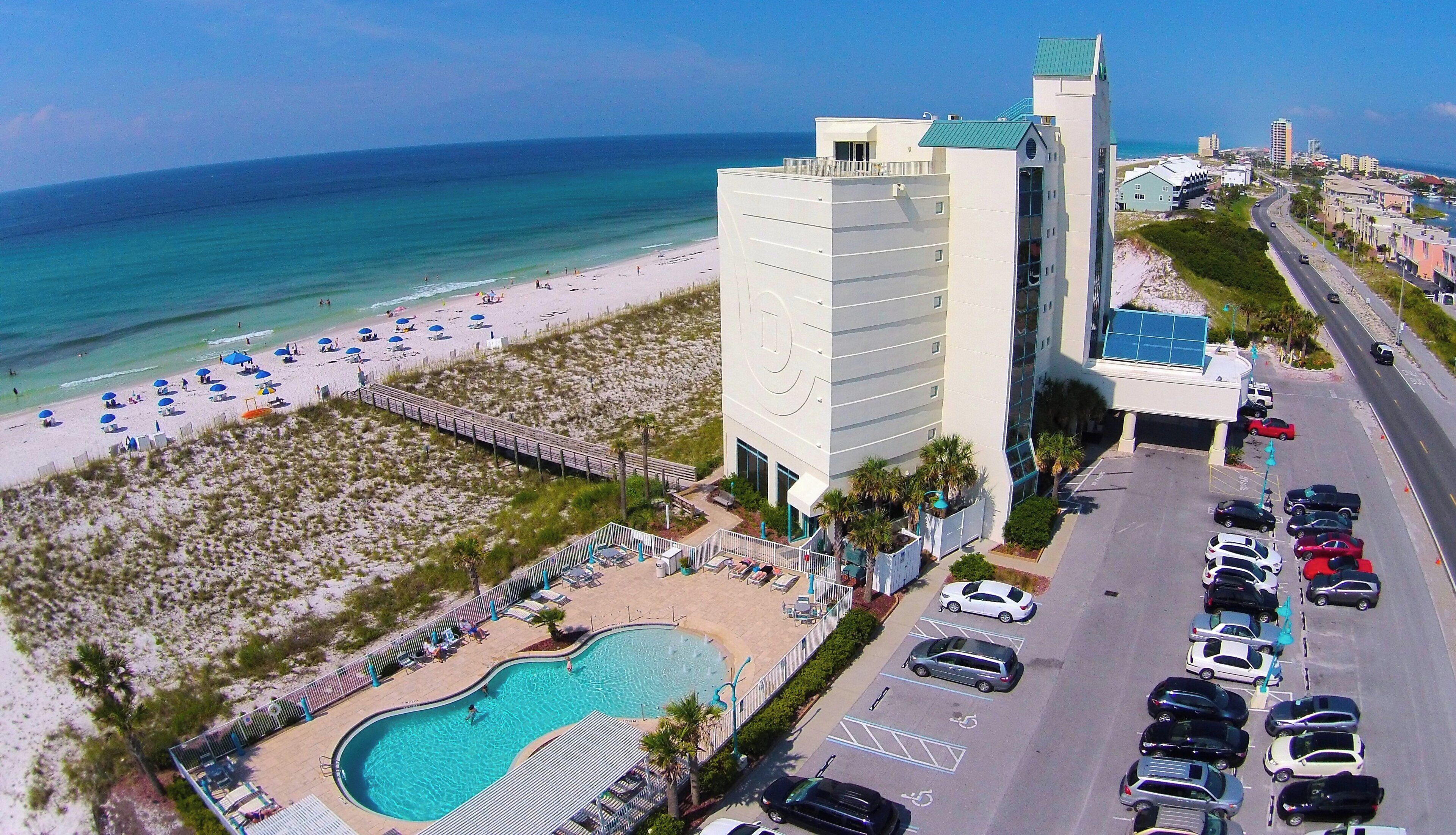 A hotel with a pool, beach access, and a parking lot.