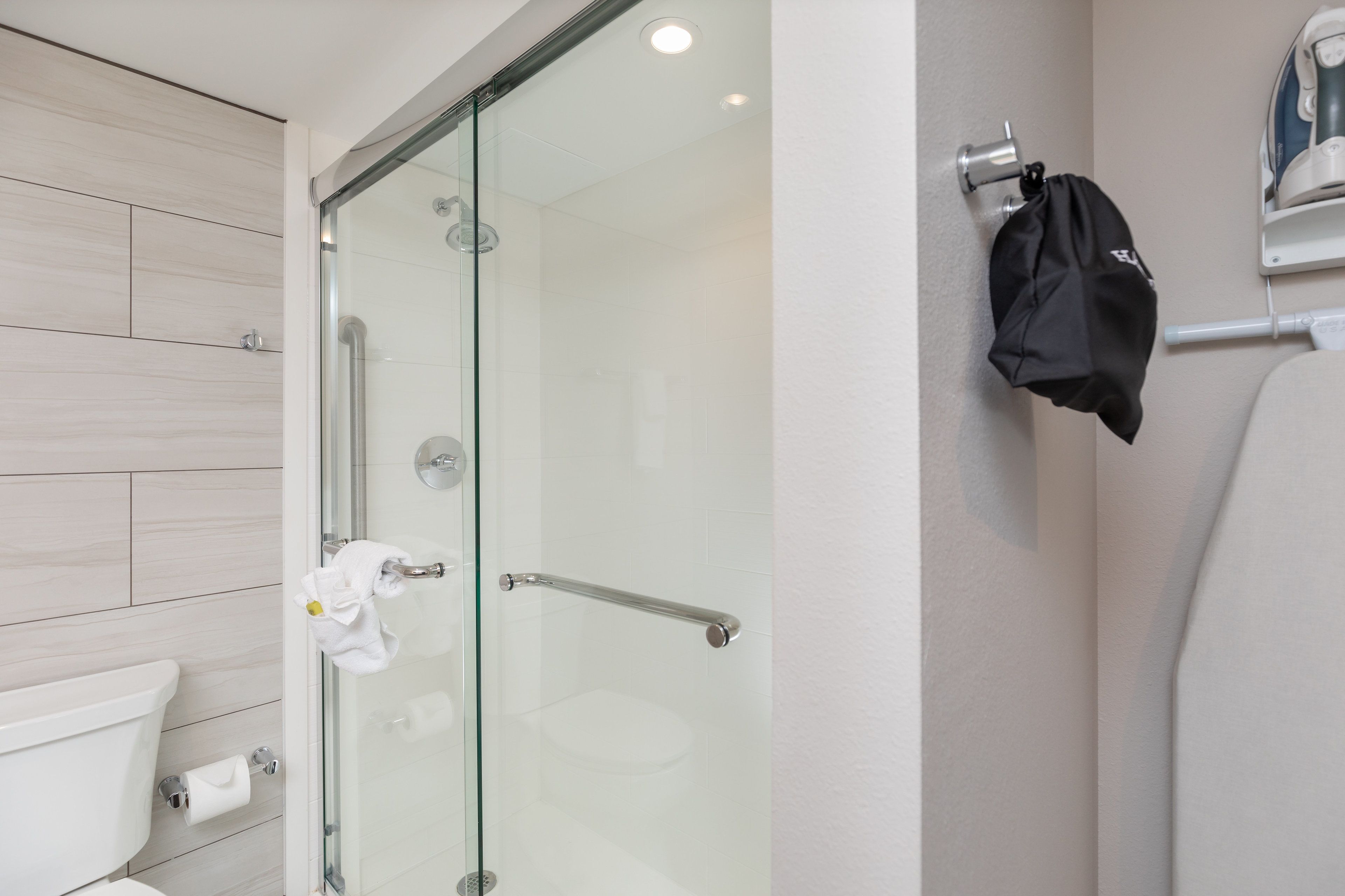 Een moderne badkamer met een douchecabine van glas, een toilet en een handdoekrek.