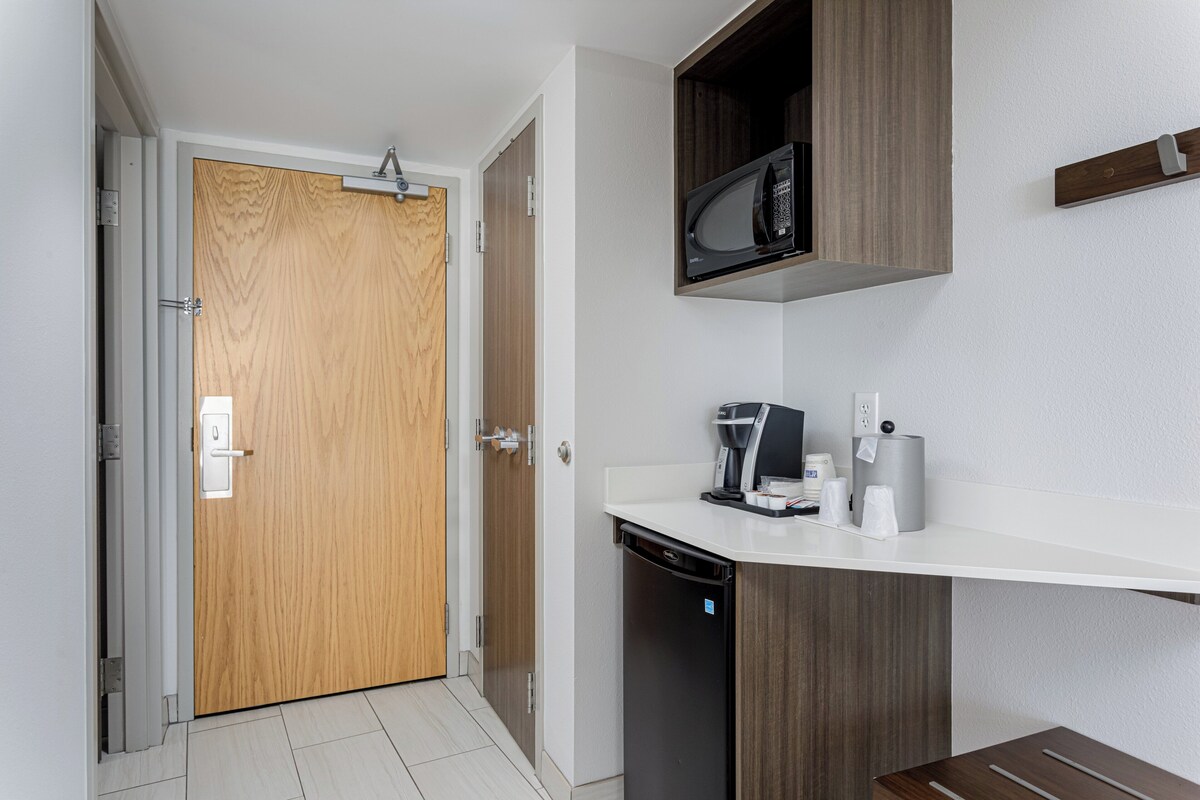 Una kitchenette compacta con microondas, cafetera y lavavajillas.